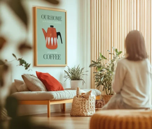 Kvinde sidder i stue med plakat af rød kaffekande og teksten "Our home runs on love, laughter and cups of strong coffee".