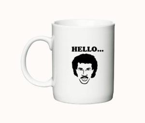 Hvidt krus med teksten "Hello... is it tea you're looking for" og en stiliseret illustration af Lionel Richie.