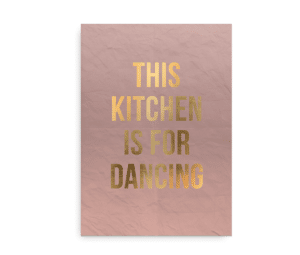 Plakat med rosa baggrund og teksten "This Kitchen is for Dancing" i gyldne bogstaver.