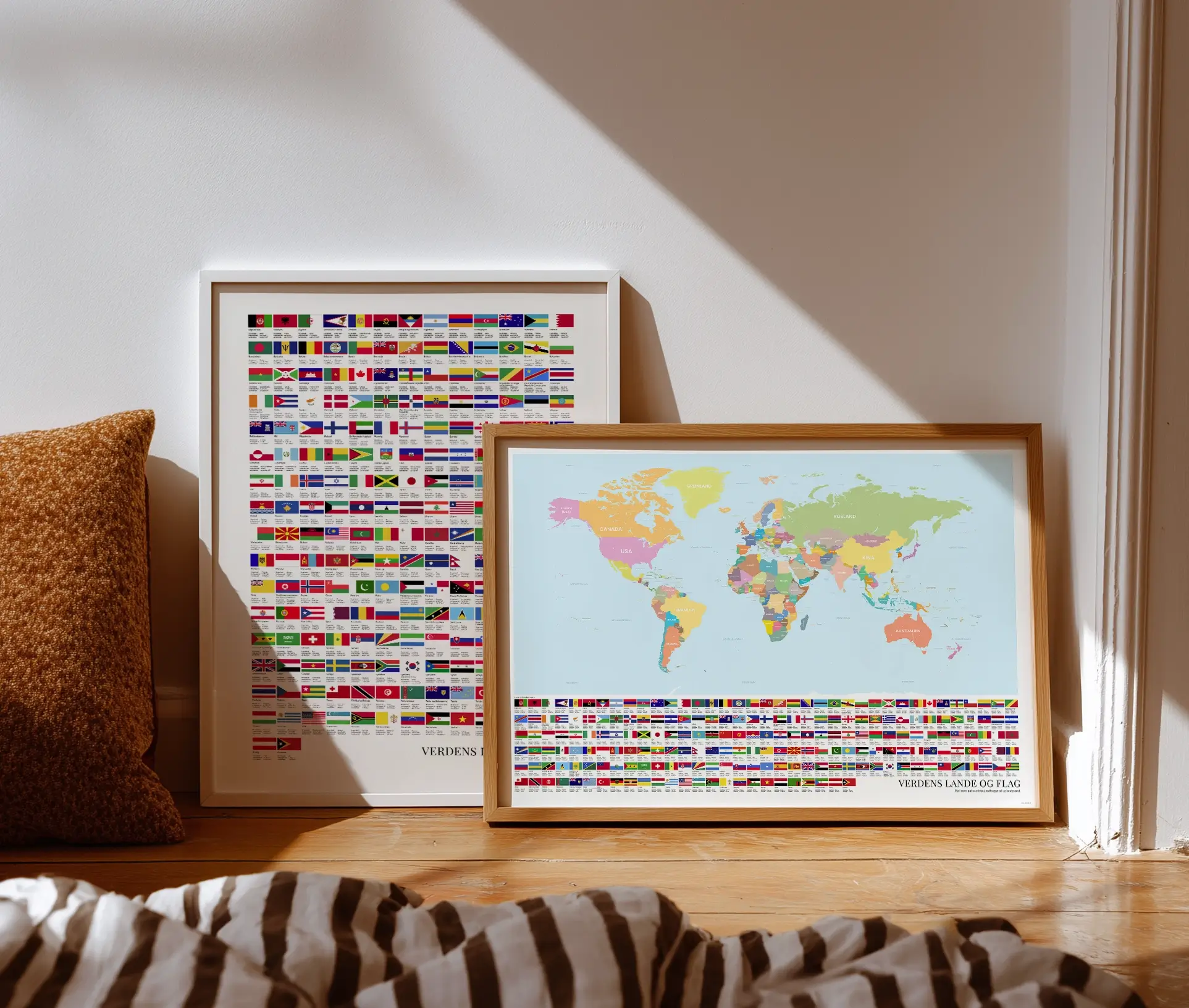 To plakater med verdenskort og flag, stående mod væg i naturligt lys – farverige og lærerige verdenskort med navne og landenes flag