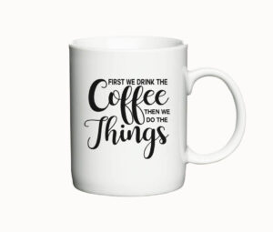 Hvidt krus med teksten "First we drink the coffee, then we do the things" i sort skrift.