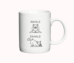 Hvidt keramisk krus med illustrationer af en hund i yoga-stilling og teksten "Inhale" og "Exhale".
