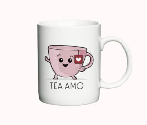 Hvidt keramisk krus med illustration af et smilende lyserødt tekrus med en tepose og teksten "Tea Amo" i sort skrift.
