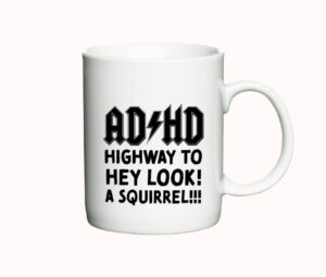 Hvid kaffekop med humoristisk tekst: "AD/HD Highway to Hey Look! A Squirrel!!!" i sort tryk.