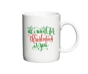 Hvid kaffekop med teksten "All I want for Christmas is you" i rød og grøn med juletema.