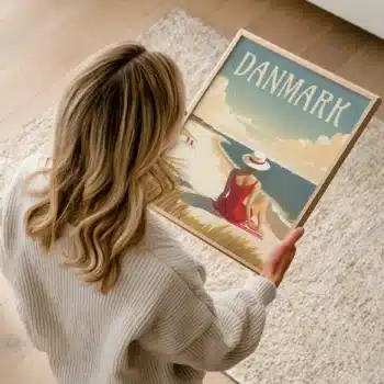 Kvinde holder en "Danmark – Vestkysten plakat" med motiv af kvinde i rød badedragt på stranden.