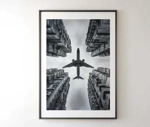 Moderne kunstplakat med minimalistisk motiv af et fly og høje bygninger.