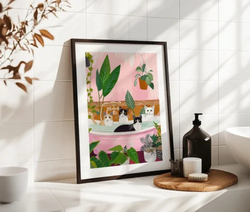 Farverig plakat med katte i badekar omgivet af grønne planter, stående på badeværelsesbord.