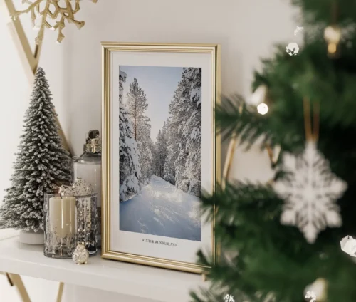Winter Wonderland fotoplakat i guldramme, placeret på en hylde med julepynt og et lille kunstigt juletræ.