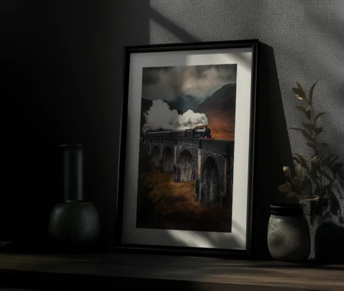Indrammet Glenfinnan Viadukt-plakat placeret på en hylde i en mørk, stemningsfuld indretning.
