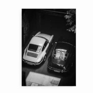 Sort-hvid plakat med to klassiske Porsche-biler parkeret side om side.