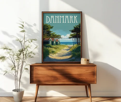 Plakat af danske sommerhuse ved havet, placeret på et træmøbel i en lys stue.
