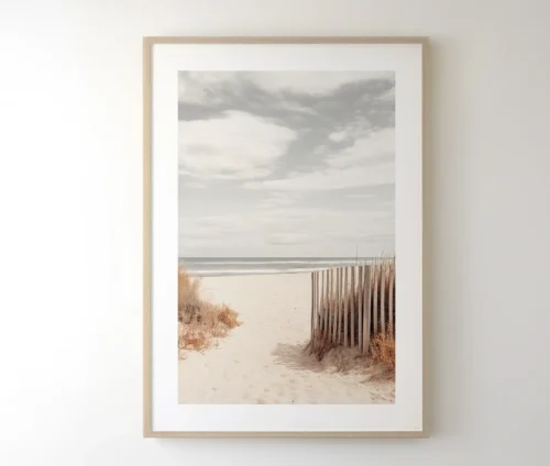 Muted beach scene plakat i lys træramme, hængende på en væg.