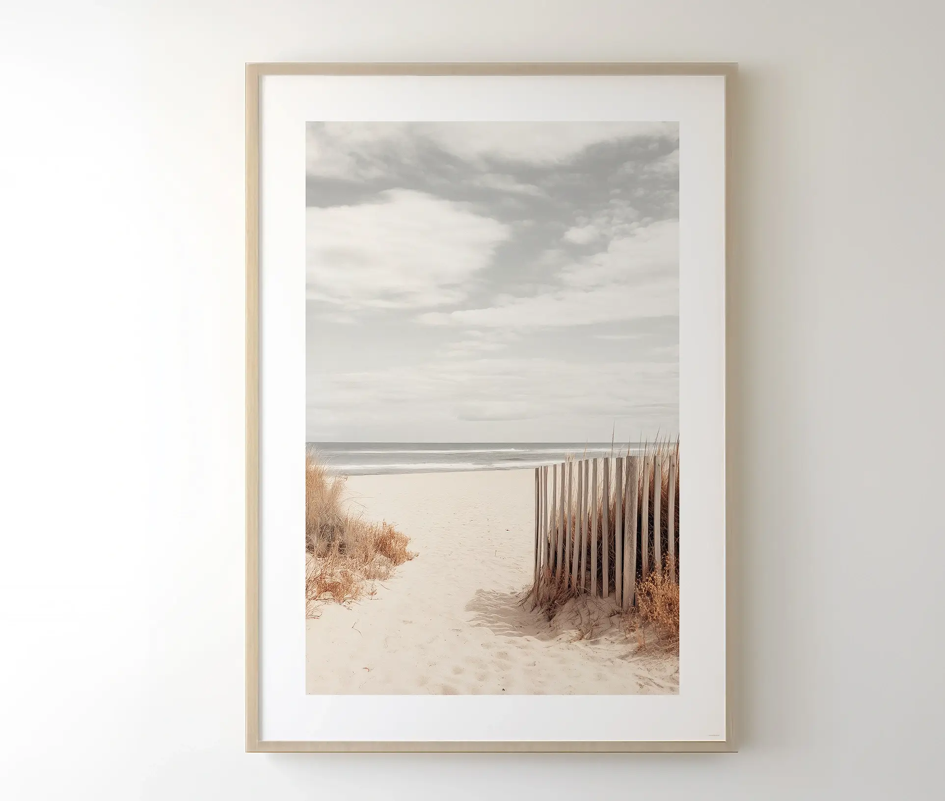 Muted beach scene plakat i lys træramme, hængende på en væg.