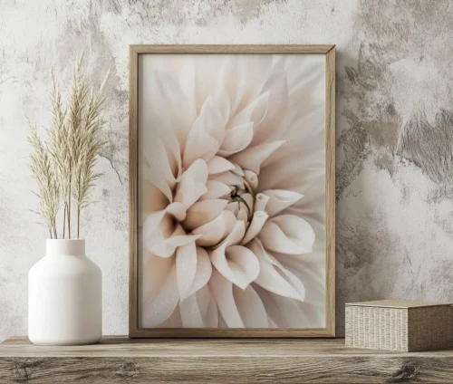 Plakat med en blød beige dahlia i en træramme, placeret på en hylde ved siden af en vase med tørrede blomster.