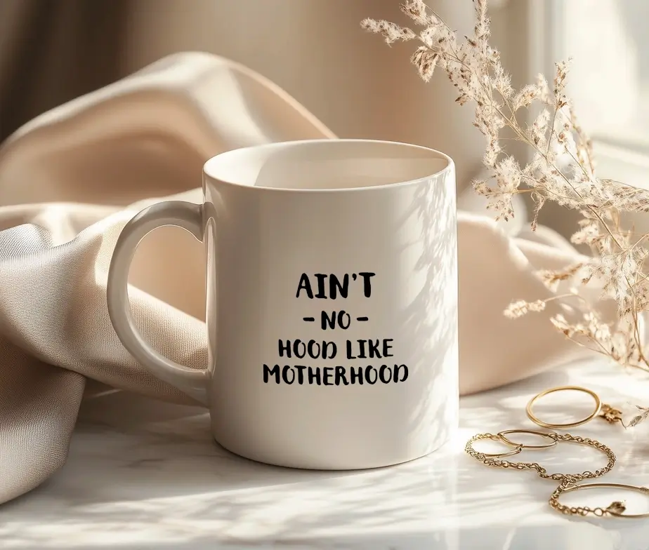Hvidt kaffekrus med teksten Ain’t No Hood Like Motherhood trykt i sort.