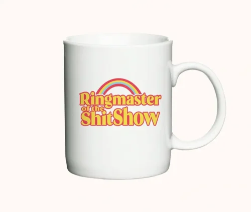 Hvidt krus med teksten "Ringmaster of the ShitShow" i retro-stil og en farverig regnbue.