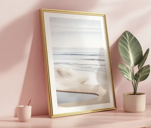 Plakat med strandmotiv i ramme, opstillet på bord