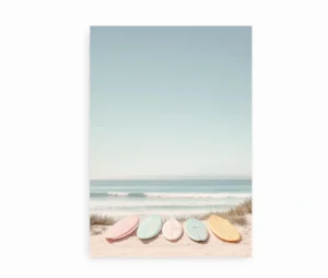 Plakat med pastelfarvede surfbrætter placeret i sandet ved stranden.