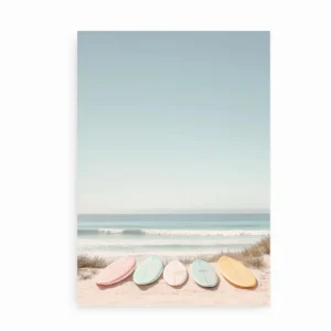 Plakat med pastelfarvede surfbrætter placeret i sandet ved stranden.