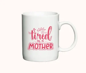 Keramikkrus med teksten "Tired as a Mother", lyserød skrift på hvid baggrund.