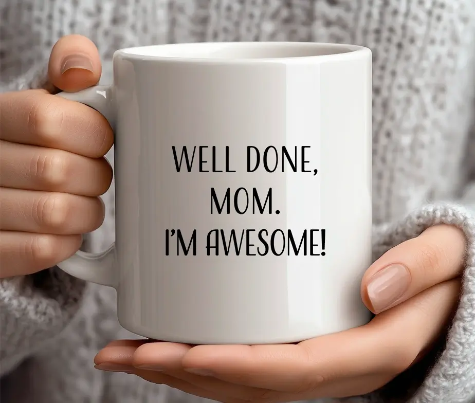 Person holder et hvidt krus med teksten Well Done, Mom. I'm Awesome!