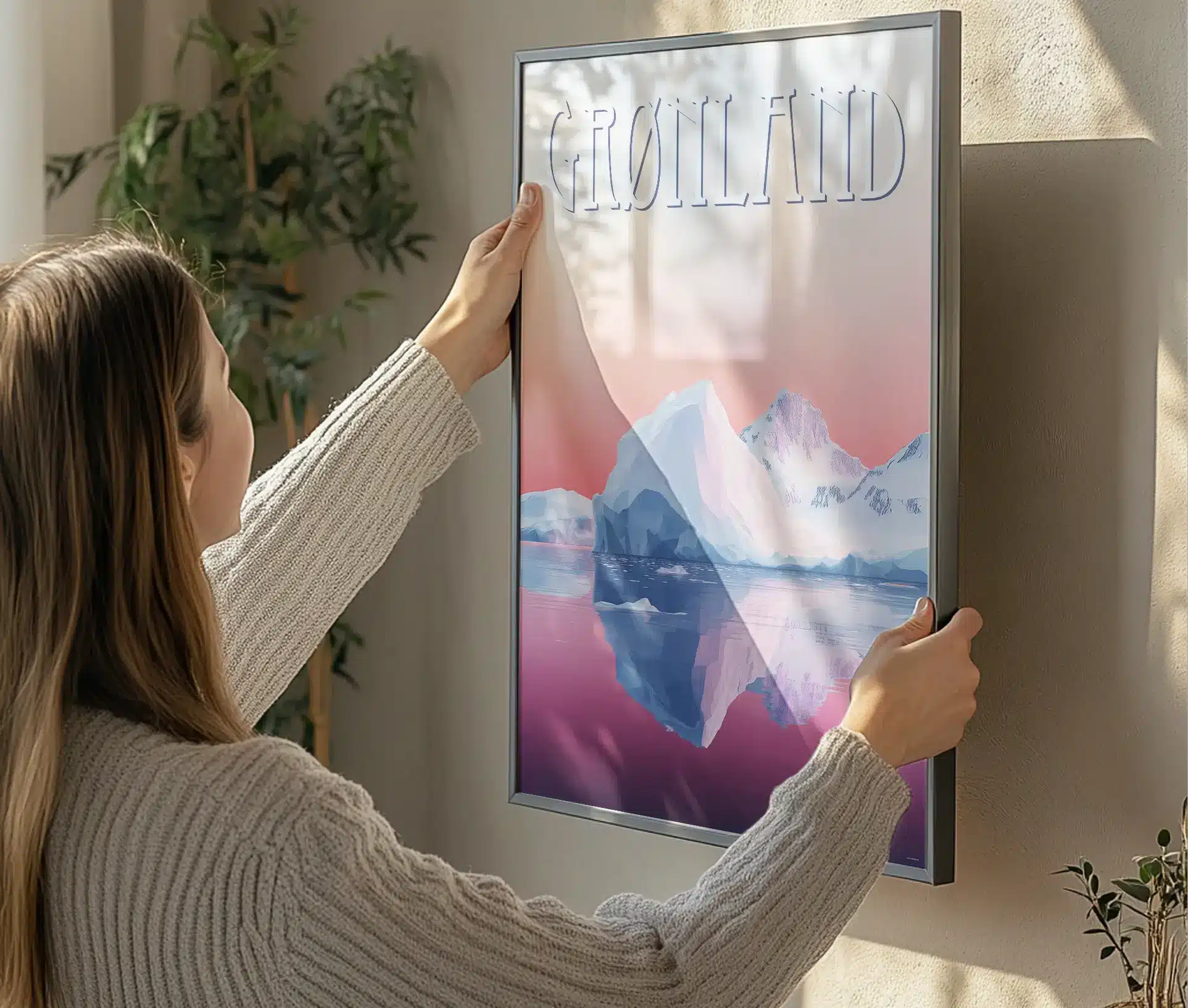 Kvinde hænger plakat op med isbjerg og Grønland-motiv
