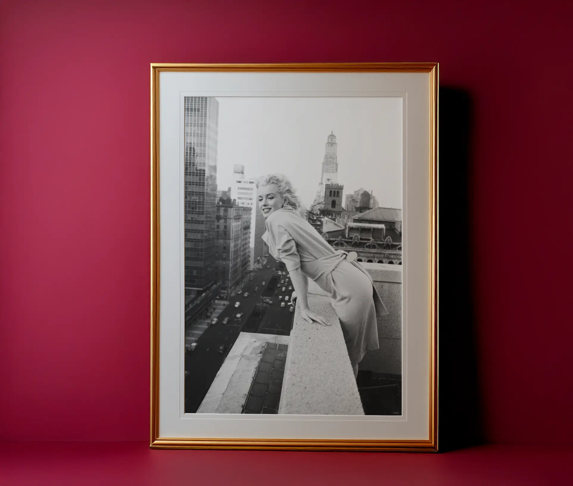 Sort-hvid plakat med Marilyn Monroe på tagterrasse i guldramme foran rød væg