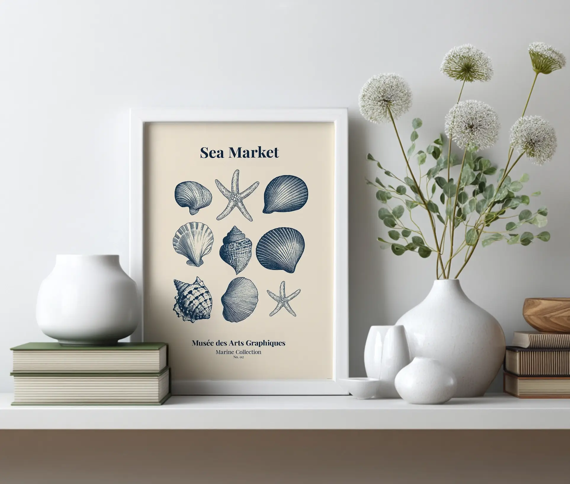 Plakat med søstjerner og muslingeskaller placeret på hylde ved siden af vaser og bøger.