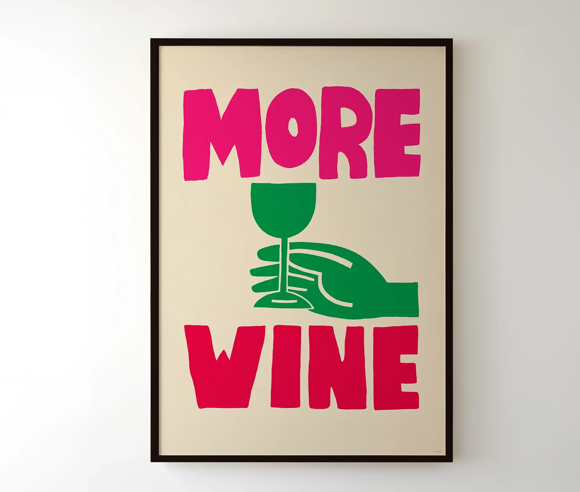 "More Wine"-plakat i sort ramme hængende på væg