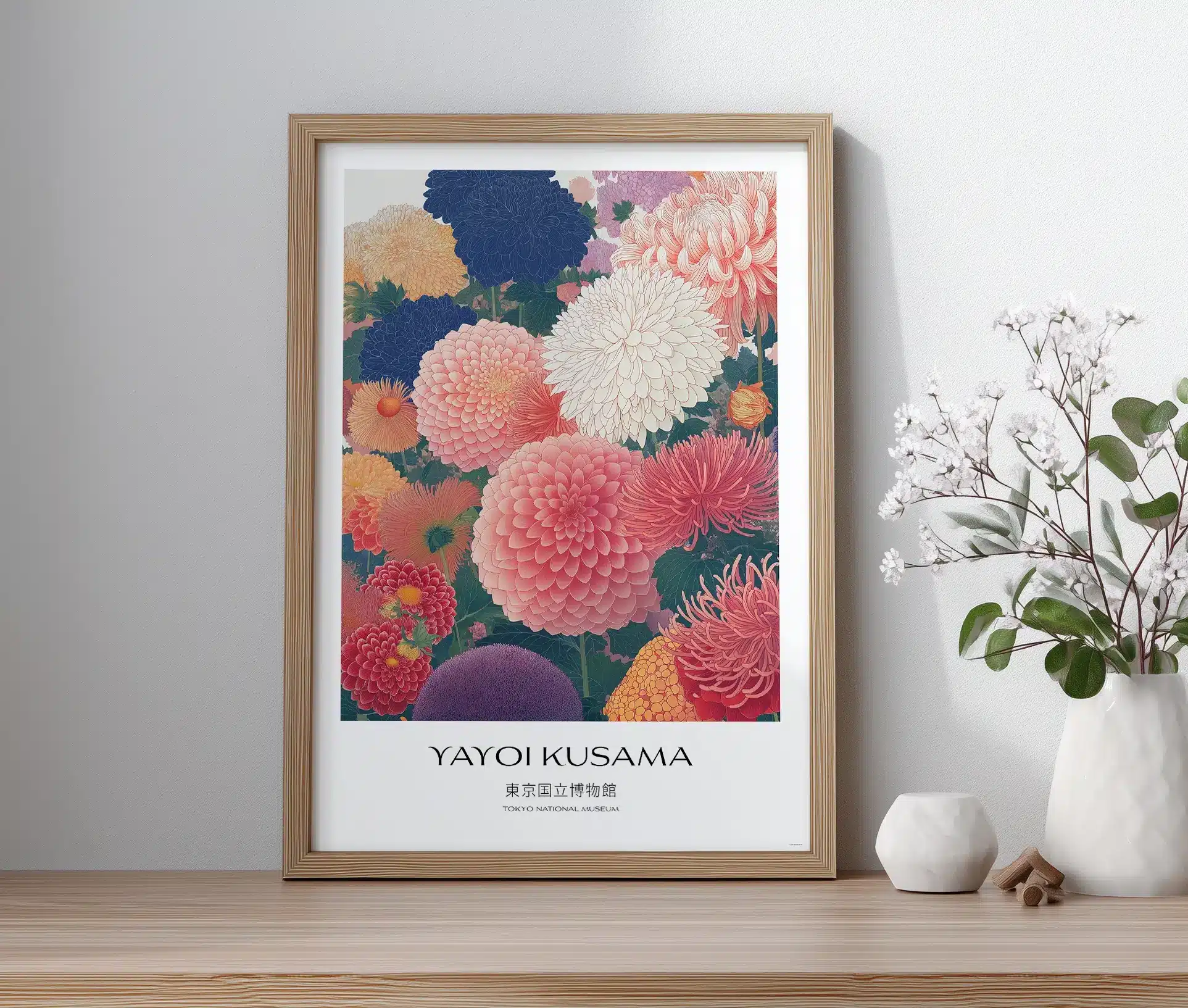 Plakat med blomsterillustration og teksten "Yayoi Kusama", vist i ramme på bord