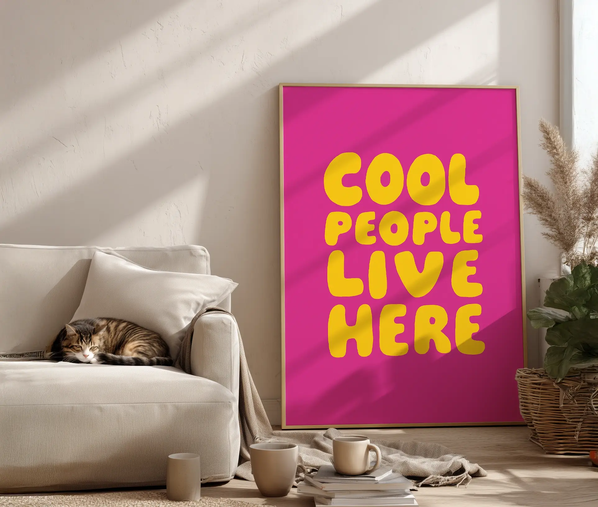 Plakat med “Cool People Live Here”-tekst lænet op ad væg ved sofa