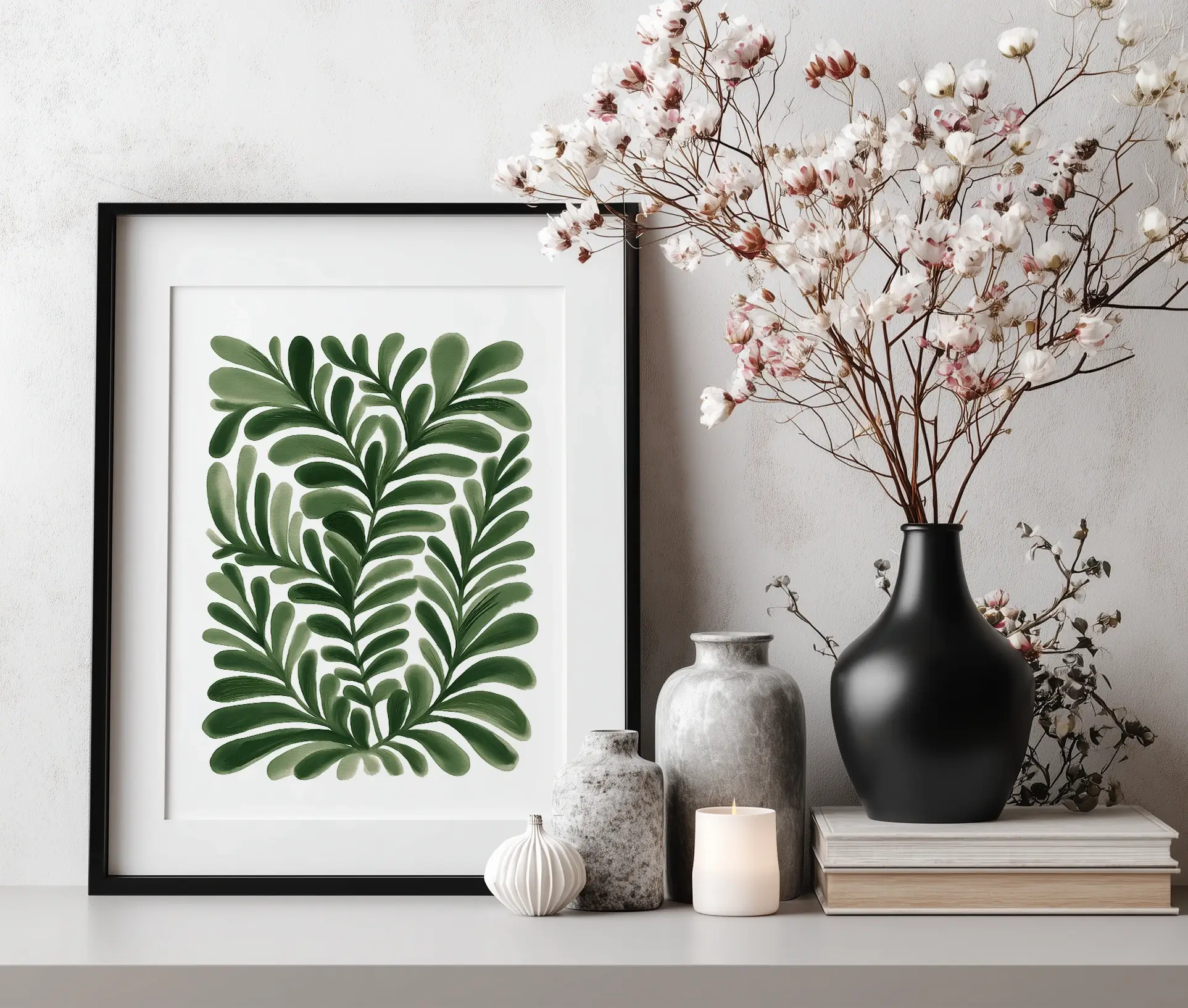 Plakat med grønne blade i sort ramme placeret ved dekoration