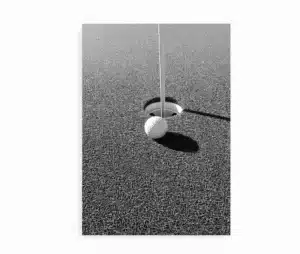 Sort/hvid plakat med golfbold tæt på hul. Minimalistisk foto med skygger og struktur.