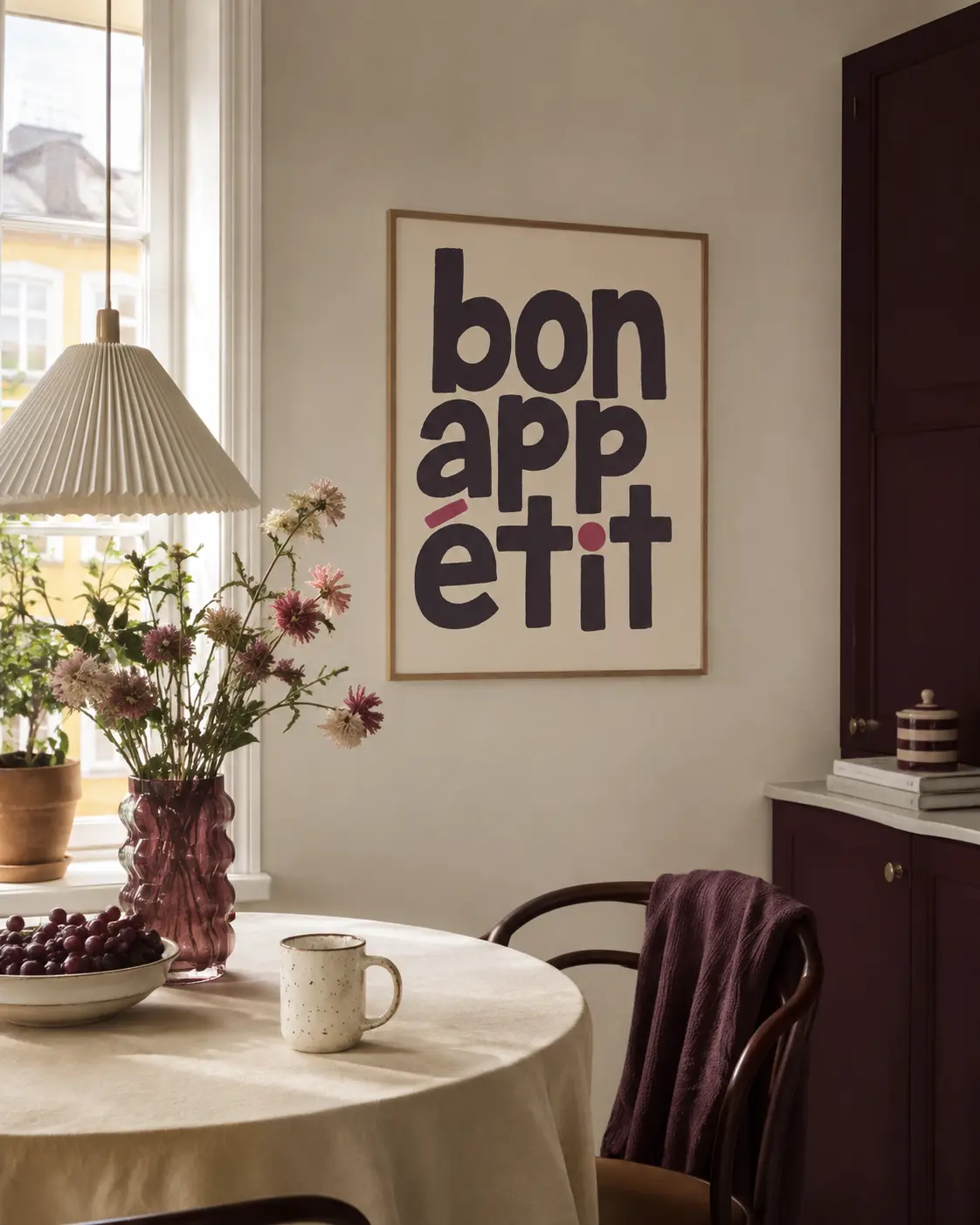 Bon Appétit plakat ophængt i hyggeligt køkken med vinrøde skabe og blomstervase